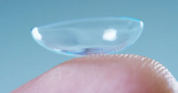Macro tiro de um dedo segurando uma tecnologia de lente de contato com um chip para ver melhor em ambos os olhos e aumentar diopters. Conceito: exame oftalmológico, tecnologia óptica, imersiva — Fotografia de Stock