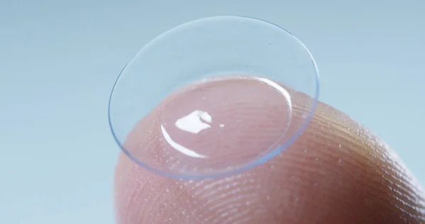 Macro tiro de um dedo segurando uma tecnologia de lente de contato com um chip para ver melhor em ambos os olhos e aumentar diopters. Conceito: exame oftalmológico, tecnologia óptica, imersiva — Fotografia de Stock