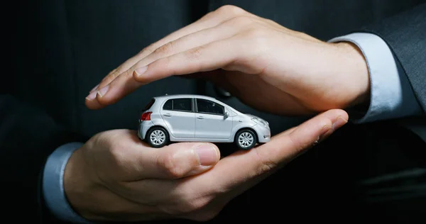 Bir takım elbise ve kravat, giymiş bir adam küçük bir otomatik gösterir. Konsept: araba sigortası, mekanik, Finansal Kiralama, satın yeni ve kullanılmış otomobil ve ortak garajlar.