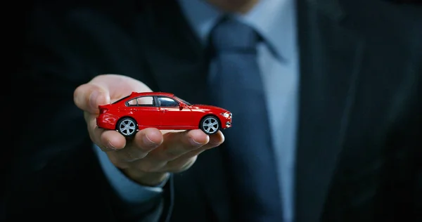 Bir takım elbise ve kravat, giymiş bir adam küçük bir otomatik gösterir. Konsept: araba sigortası, mekanik, Finansal Kiralama, satın yeni ve kullanılmış otomobil ve ortak garajlar.