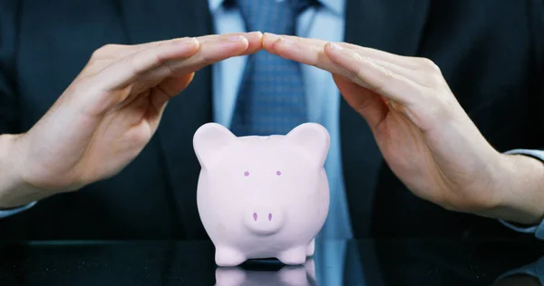 A man dressed in a suit and tie, puts money into the piggy bank. Concept: Pension, savings, investment, accumulation plan, savings for college studies. — Stock Photo, Image