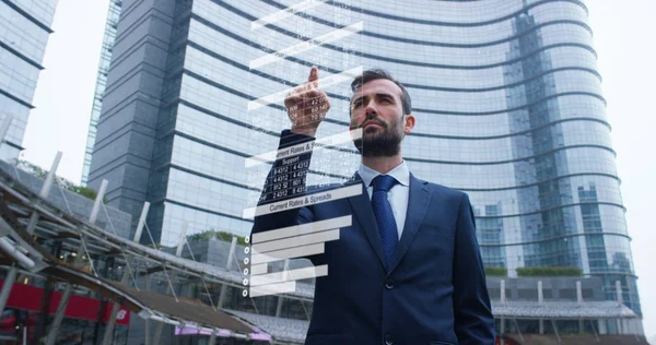 Бізнесмен у костюмі використовує голографію та доповнену реальність, щоб побачити в 3D-графіці фінансову економіку в своєму офісі в хмарочосі . — стокове фото