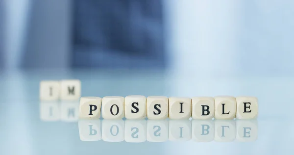 Eine Hand verwandelt das Wort "unmöglich" in "möglich" und wirft die Buchstaben weg. Konzept: Engagement, bis zum Ende daran glauben, alles ist möglich. — Stockfoto