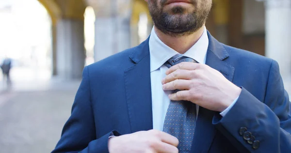 In città un uomo elegante sistema giacca abito e cravatta prima di andare al lavoro o ad una cerimonia, concetto: moda, affari, celebrazione, eleganza, lavoro e città — Foto Stock