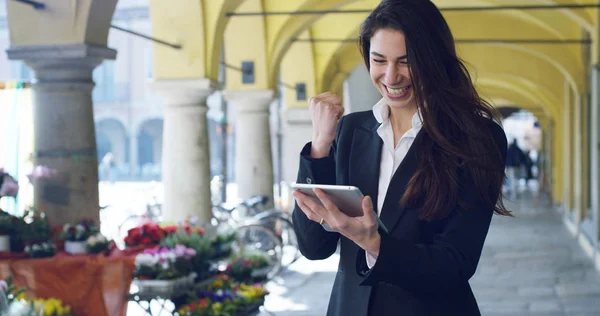 Una hermosa mujer de carrera utiliza tableta o teléfono inteligente, en el fondo de la ciudad. La empresaria sonríe mientras lee correos electrónicos y mensajes de trabajo. Concepto: tecnología, negocio, tableta — Foto de Stock