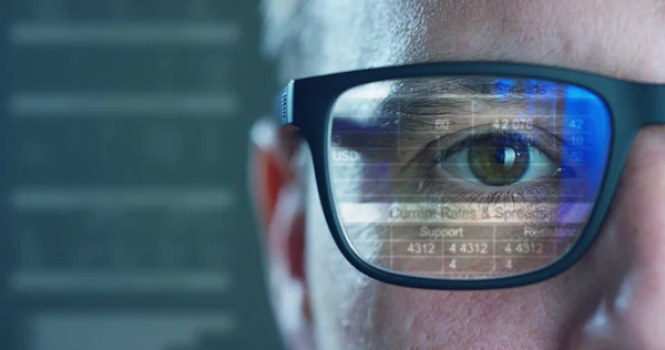 Close up de jovem empresário com olhos azuis vestindo os óculos olhando linhas de forma de onda expressando conceitos de mercado de ações, realidade aumentada, tecnologia, bolsa de valores e finanças — Fotografia de Stock