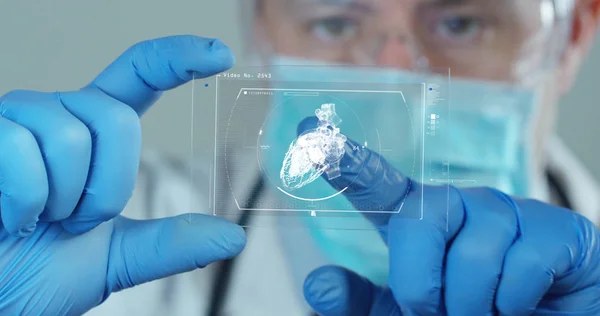 A physician, surgeon, examines a technological digital holographic plate represented the patient's body, the heart lungs, muscles, bones. Concept: Futuristic medicine, world assistance, and the future — Stock Photo, Image