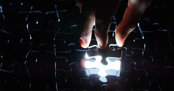 A creative completes the black or white light puzzle putting the last missing piece. Concept: cooperation, teamwork, creativity, and access solution. — Stock Photo, Image