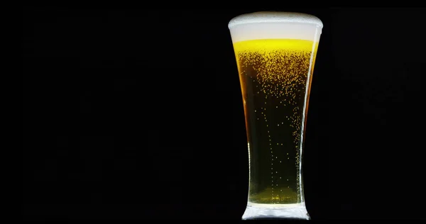 Lento movimento macro ainda vida da cerveja espumada derramado em vidro transparente isolado no fundo preto (close-up ) — Fotografia de Stock