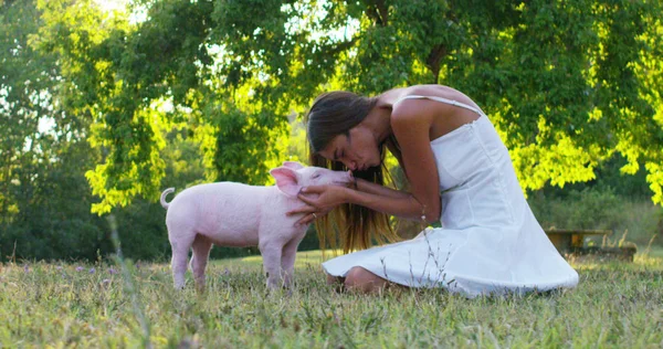 Menina acaricia e beija um porco leitão. mundo perfeito e verde. sustentabilidade e amor à natureza, respeito ao mundo e amor aos animais. conceito de vegan ou vegetariano. ligação ao mundo — Fotografia de Stock