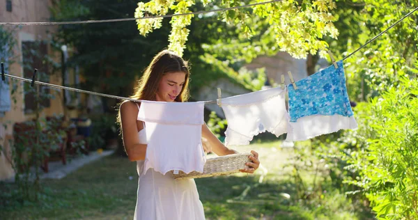 Mujer joven bebe al atardecer en un mundo verde estira los zapatos al aire libre. la ropa está perfumada y limpia. concepto de sostenibilidad, naturaleza y pureza y limpieza profunda después del lavado. Trabajos domésticos — Foto de Stock