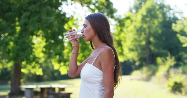 Jeune femme boit au coucher du soleil dans un monde vert une tasse d'eau froide et pure. concept de durabilité, la nature et la pureté de l'eau douce et purifié — Photo