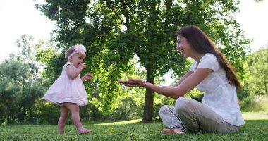 güzel ve mutlu güneşli bir gün, anne ve bebek küçük bir kız oynamak ve renkli doğada dalmış mutluyuz ve mutluluk, Bebek mutlu gülüyor. mutluluk, aşk ve doğa kavramı.