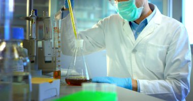 güzel genç bilim adamı erkek doktor sıvı virüs hücreleri kullanarak nitelikli ekipman ve gözleri korumak için gözlük takan ve laboratuvar bardak bakımı profesyonel Laboratuvar analiz