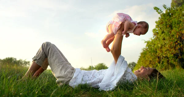 En un hermoso y feliz día soleado, una madre y una niña juegan y son felices inmersos en la naturaleza colorida y la felicidad, el bebé ríe feliz. concepto de felicidad, amor y naturaleza . —  Fotos de Stock