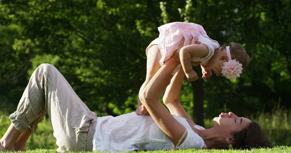 Par une belle et heureuse journée ensoleillée, une mère et une petite fille jouent et sont heureux immergés dans la nature colorée et le bonheur, le bébé rit heureux. concept de bonheur, d'amour et de nature . — Photo