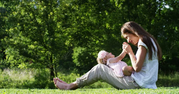 En un hermoso y feliz día soleado, una madre y una niña juegan y son felices inmersos en la naturaleza colorida y la felicidad, el bebé ríe feliz. concepto de felicidad, amor y naturaleza . —  Fotos de Stock