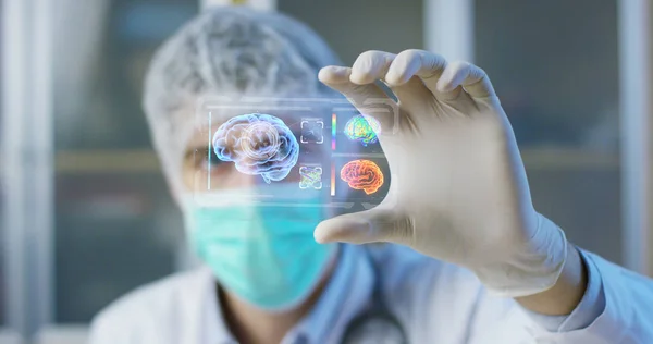 Un médico, cirujano, examina una placa holográfica digital tecnológica representada el cuerpo del paciente, los pulmones del corazón, los músculos, los huesos. Concepto: La medicina futurista, el cuerpo humano y el futuro . —  Fotos de Stock