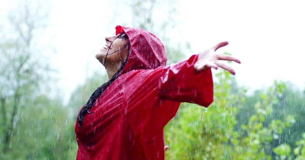 Menina sorri, gira e ri na chuva. a chuva cai, as gotas caem em seu rosto e a menina está feliz com a vida e a natureza ao redor. conceito de natureza e vida feliz. Aventura, pureza . — Fotografia de Stock