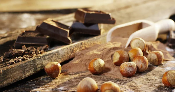 Une chute de noisettes au ralenti et en arrière-plan, chocolat noir, cacao en poudre. Concept d'hiver, noisettes, chocolat . — Photo