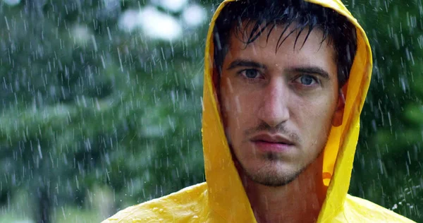 Um homem sob a chuva forte, ele olha para cima desafiadoramente com um olhar forte e desagradável para o desafio. Conceito de esporte, extremo, chuva, fadiga, beleza . — Fotografia de Stock