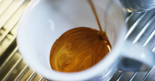 Kopi espresso dari Italia berkualitas tinggi yang dibuat dengan mesin kopi profesional jatuh ke dalam porselen cangkir kopi dalam gerakan lambat. konsep Italia, santai, bio dan alam — Stok Foto