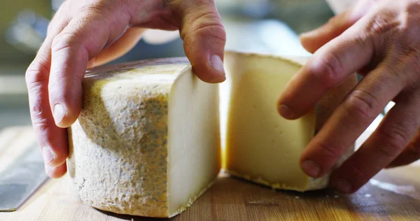 Las manos del chef tienen un típico queso italiano / francés en una tabla de cortar tradicional. concepto de artesanía y queso fresco y saludable. biológico y genuino — Foto de Stock