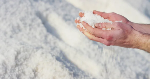 Рука маленького мальчика, разбрасывающего соль и выводящего на свет очень большую гору соли и промышленного сырья в замедленном режиме в солнечный день — стоковое фото