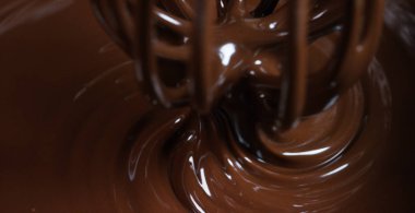 Lezzetli kahverengi çikolata şekerleme, çikolata bir arka plan üzerinde yapım profesyonel bir fabrikada bir makine tarafından engellenir. Konsept: tatlılık, krema, çikolata, lezzetli hava, gurme üretimi.