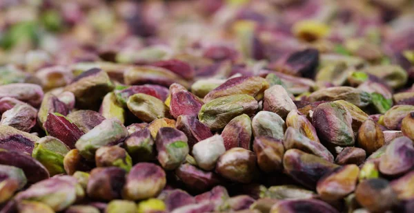 Man raakt kleurrijke schoongemaakte pistache groen, paars, geel. Concept: gezouten, noten, zaden, heerlijke, gezonde, groeiende op de "tree of life", vers product, groeiende in Centraal-Azië, goede voeding — Stockfoto