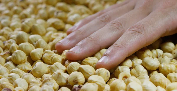 Close-up of a man touching peeled light yellow hazelnuts. Concept: salted, nuts, seeds, tasty, healthy, fresh product, proper nutrition and energy, bush of the genus Leshchina of the Birch family. — Stock Photo, Image