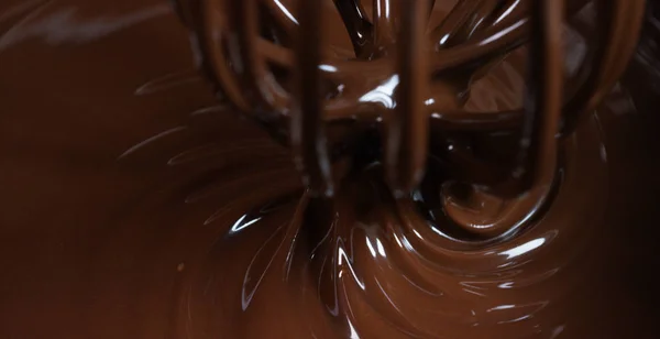 Delicioso chocolate marrón es impedido por una máquina en una fábrica profesional haciendo dulces, sobre un fondo de chocolate. Concepto: la producción de dulzura, crema, chocolate, aire delicioso, gourmet . —  Fotos de Stock