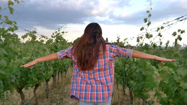 Hermosa niña (mujer) agricultor sonriendo viendo los campos de uva, se siente la libertad, en una camisa, fondo verde. Concepto: ecología, vino, bio-producto, inspección, agua, productos naturales, agricultura . — Foto de Stock