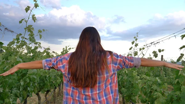 Hermosa niña (mujer) agricultor sonriendo viendo los campos de uva, se siente la libertad, en una camisa, fondo verde. Concepto: ecología, vino, bio-producto, inspección, agua, productos naturales, agricultura . — Foto de Stock