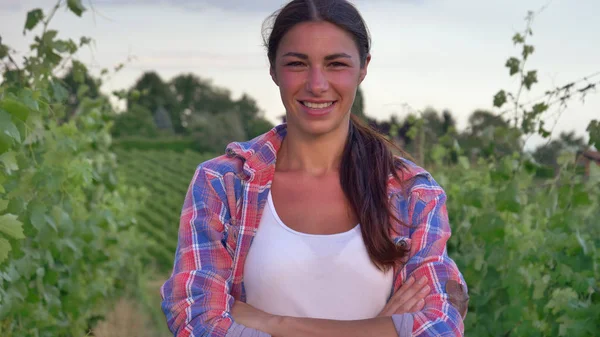 Hermosa niña (mujer) agricultor sonriendo viendo los campos de uva, en una camiseta blanca, en una camisa, fondo verde Concepto ecología, vino, bio producto, inspección, agua, productos naturales, agricultura — Foto de Stock