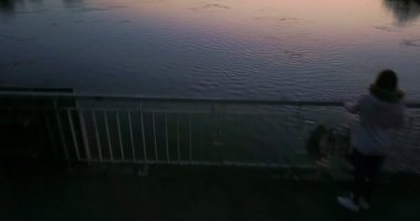 Köprü ve nehir kıyısında günbatımı güzel uçuş. bir kız nehirde seyir köprüsü üzerinde duruyor. manzara