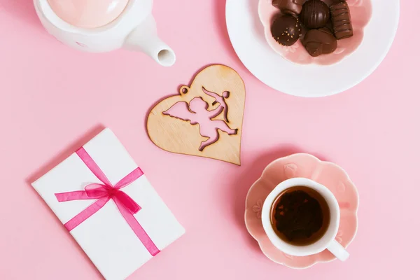 Подарок ко Дню святого Валентина с чаем и чашечками на розовом фоне. Вид сверху, эффект пленки — стоковое фото