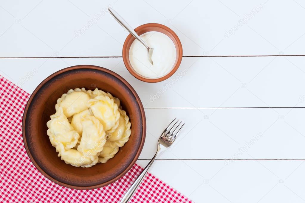 Sweet pierogi with sour cream, on red napkin and white background