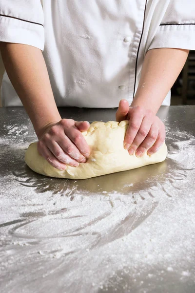 Woman knead the dough in bakery, on a table from steel. Working process — Stock Photo, Image