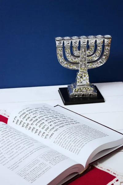 Livro judaico com um castiçal na mesa e fundo azul. Imagem tonificada, processamento de autor — Fotografia de Stock