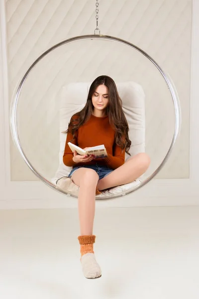 Uzun saçlı güzel kız kitap, kolye sandalyede okuyor. İç, tonlu görüntü ana sayfa, işlem yazar