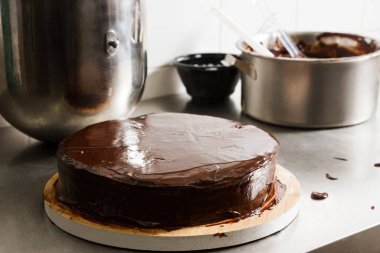 Prepared chocolate cake with glaze icing, final stage of cooking. The process of making the chocolate cake, from begin to the end. Made by hands for confectionery.