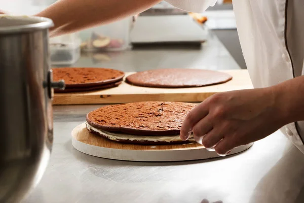 Woman is preparing chocolate cake with milk cream. The process of making the chocolate cake, from begin to the end. Made by hands for confectionery.