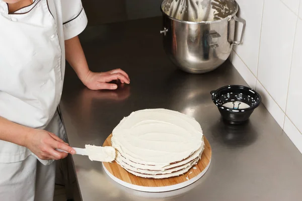 Mulher está preparando bolo de chocolate com creme de leite. O processo de fazer o bolo de chocolate, do início ao fim. Feito por mãos para confeitaria . Fotografia De Stock