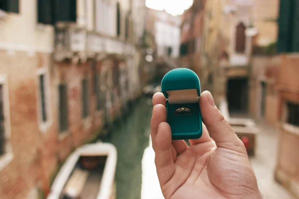 Stock image Man holding a blue box with engagement ring front venetian canal. An offer of marriage in Venice, Italy. Film effect, author processing of photo.