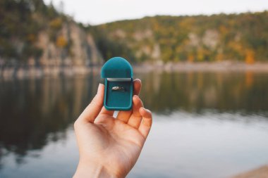 Elinde nişan yüzüğüyle güzel manzaralı mavi bir kulübe tutan bir kadın. Çek Cumhuriyeti 'ndeki Zvikov Kalesi' nde evlenme teklifi. Film efekti, fotoğraf yazma işlemi
