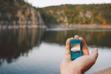 Elinde nişan yüzüğüyle güzel manzaralı mavi bir kulübe tutan adam. Çek Cumhuriyeti 'ndeki Zvikov Kalesi' nde evlenme teklifi. Film efekti, fotoğraf yazma işlemi