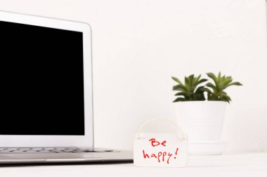 Diz üstü bilgisayarın ve beyaz duvarın önündeki tahta zeminde motivasyon sloganı. Siyah ekran, boşluğu kopyala.