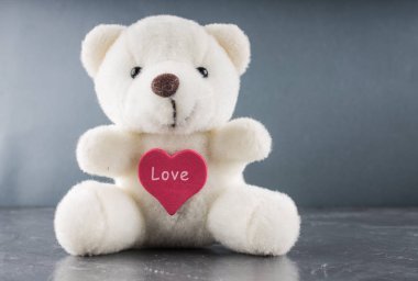 White teddy bear with love letter on red heart  gray background. Say i  you for valentine 's day concept. clipart