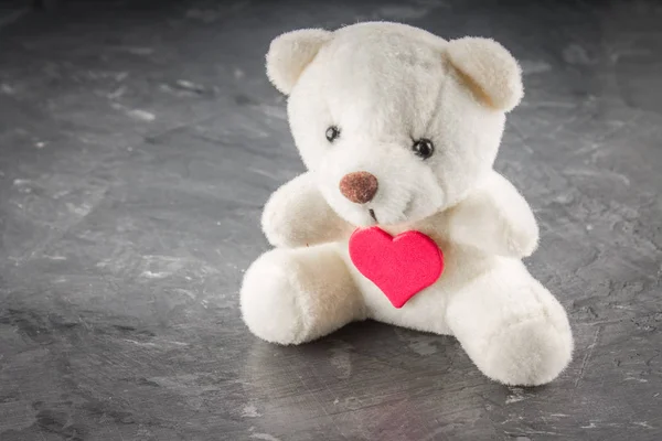 Λευκό αρκουδάκι με επιστολή αγάπης στο κόκκινο καρδιά γκρι φόντο. Πω για ημέρα του Αγίου Βαλεντίνου έννοια. — Φωτογραφία Αρχείου